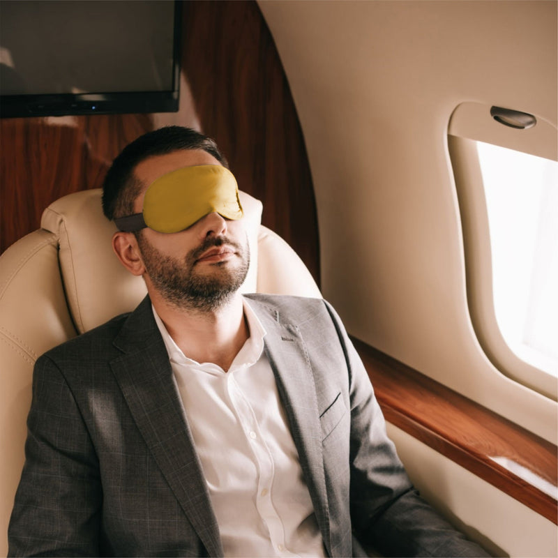 a guy is wearing eye pillow in airplane